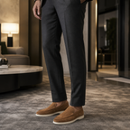 Men's brown suede loafers styled in a hotel lounge