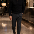 Men's black textured polo sweater styled in a hotel lobby
