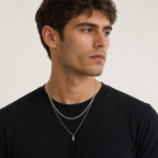 Men wearing layered silver curb and spike pendant necklaces with a black T-shirt
