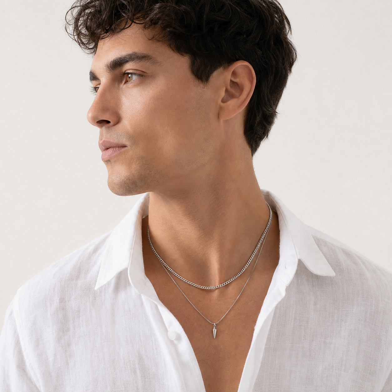 Men wearing layered silver curb and spike pendant necklaces with a linen shirt