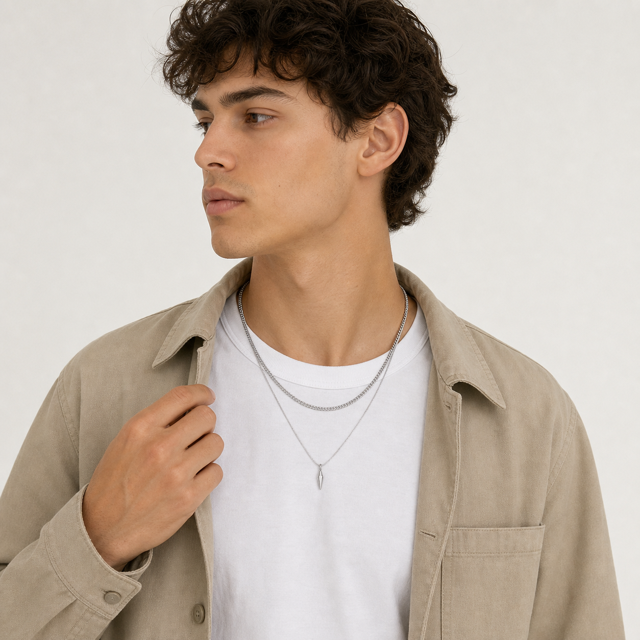 Men wearing layered silver curb and spike pendant necklaces with an overshirt