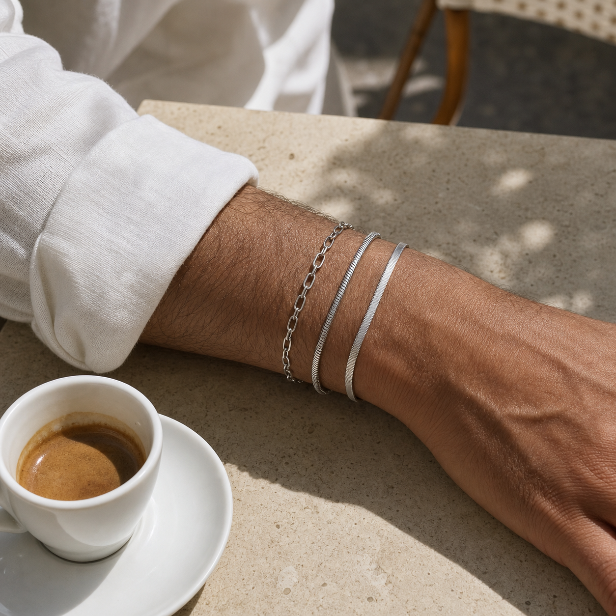 Three layered silver bracelets styled with a white linen shirt at a cafe
